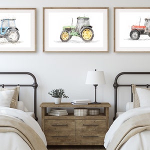 K&ouml;nnte beinhalten: Drei Aquarellbilder von Traktoren in einem Bauernhaus-Schlafzimmer. Die Traktoren sind blau, gr&uuml;n und rot. Die Bilder sind gerahmt und an der Wand &uuml;ber zwei Einzelbetten aufgeh&auml;ngt.