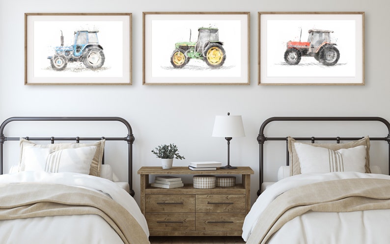 K&ouml;nnte beinhalten: Drei Aquarellbilder von Traktoren in einem Bauernhaus-Schlafzimmer. Die Traktoren sind blau, gr&uuml;n und rot. Die Bilder sind gerahmt und an der Wand &uuml;ber zwei Einzelbetten aufgeh&auml;ngt.