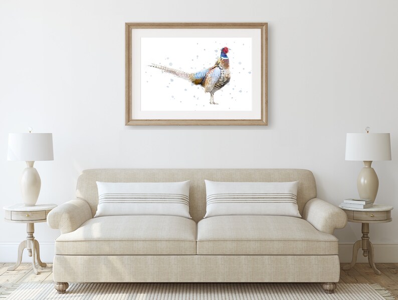 May include: A watercolor painting of a pheasant with a blue and red head and a brown, white, and black body. The pheasant is standing on a white background with a few small dots of paint.