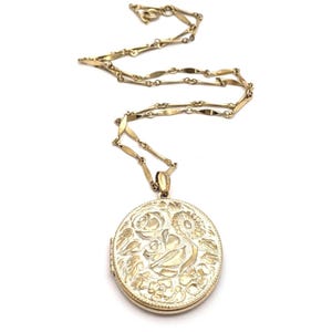 May include: Gold-toned necklace with a floral locket. The locket features an embossed design of roses and other flowers. The chain is delicate and has a unique link pattern. The necklace is displayed against a white background.