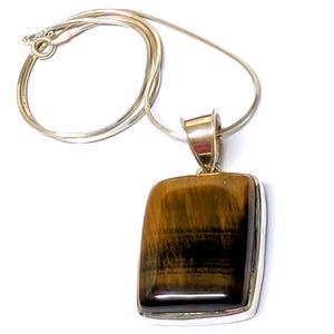 May include: A rectangular pendant necklace with a polished tiger's eye stone. The pendant is set in a silver-colored metal frame and hangs from a delicate silver chain. The tiger's eye stone has brown and gold bands.