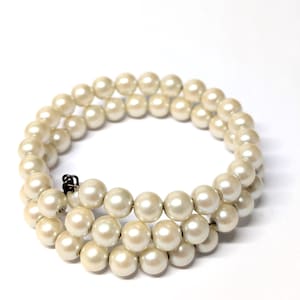 May include: A double-strand pearl necklace with a clasp. The pearls are a creamy off-white color and appear to be uniform in size. The necklace is displayed against a white background.