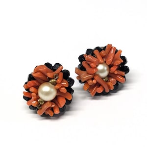 May include: A pair of earrings with a black bead base and coral branches surrounding a white pearl.