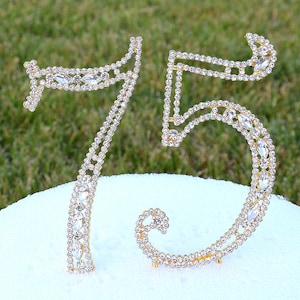 May include: Gold-tone cake topper with the numbers 75, decorated with clear rhinestones.