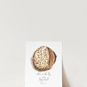 May include: A watercolor painting of a loaf of bread with a leaf design. The text "Give us this day our daily bread. Matthew 6:11" is written below the bread.
