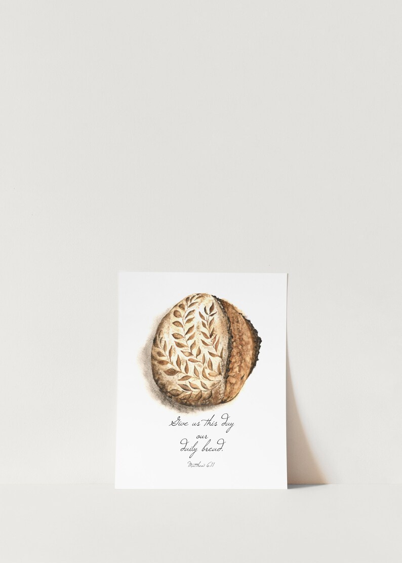 May include: A watercolor painting of a loaf of bread with a leaf design. The text "Give us this day our daily bread. Matthew 6:11" is written below the bread.