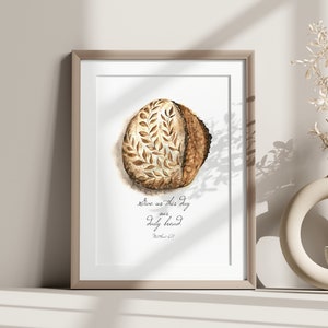 May include: A framed print with a watercolor illustration of a loaf of bread with the text "Give us this day our daily bread" and the scripture reference "Matthew 6:11".