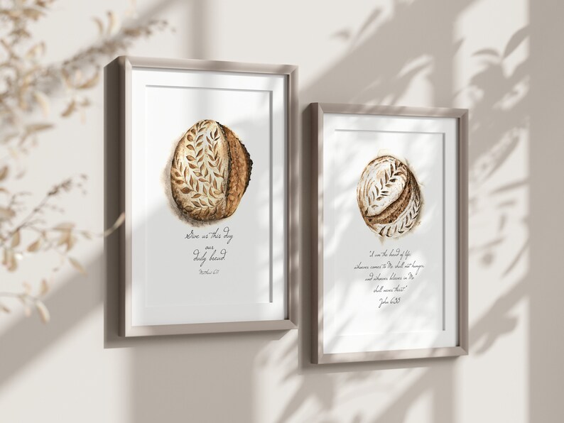 May include: Two framed prints with watercolor illustrations of sourdough bread. The first print features a loaf of bread with the text "Give us this day our daily bread" and the second print features a loaf of bread with the text "I am the bread of life, whoever comes to me shall not hunger and whoever believes in me shall never thirst."