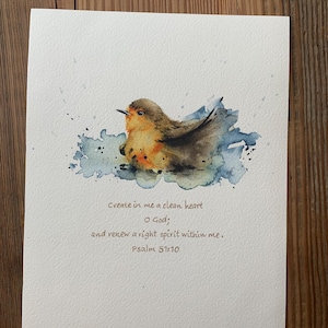 May include: Watercolor painting of a small bird with brown and orange feathers, set against a blue watercolor wash. The artwork includes the text "Create in me a clean heart O God; and renew a right spirit within me. Psalm 51:10."