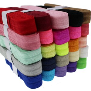 Könnte beinhalten: Ein Stapel von 18 bunten Gummibändern, jedes etwa 2,5 cm breit. Die Farben umfassen Rot, Rosa, Grün, Blau, Lila, Orange, Gelb, Schwarz, Braun und Weiß.