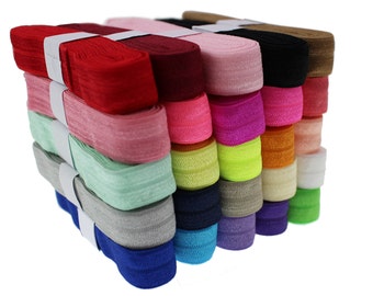 May include: A stack of 18 colorful elastic bands, each about 1 inch wide. The colors include red, pink, green, blue, purple, orange, yellow, black, brown, and white.