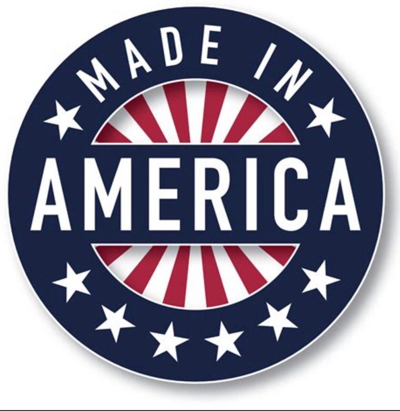 May include: A round sticker with the words "MADE IN AMERICA" in white, arched around the top of the circle. The word "AMERICA" is in large white letters in the center. The background features a blue ring with white stars and red and white stripes.