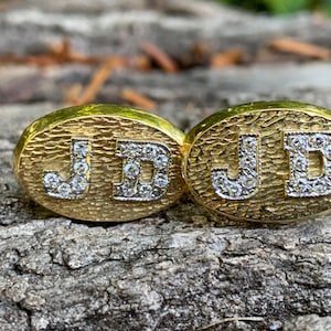 May include: A pair of gold cufflinks with the initials "JD" set in diamonds.