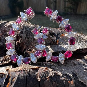 Op de afbeelding: Een paar robijn- en diamanten oorbellen. De oorbellen zijn gemaakt van witgoud en hebben een rij ronde robijnen en marquise diamanten.