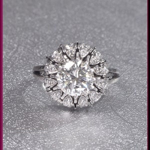May include: A silver ring with a large, round, clear diamond surrounded by smaller diamonds.