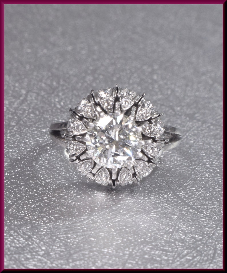 May include: A silver ring with a large, round, clear diamond surrounded by smaller diamonds.