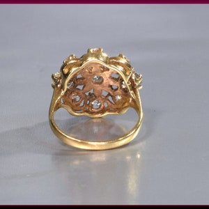 May include: A gold ring with a floral design and clear stones. The ring is set with a cluster of small stones in the center and smaller stones around the edges.