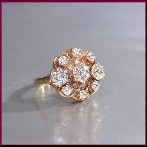 May include: A gold ring with a cluster of round, clear diamonds set in a floral design.
