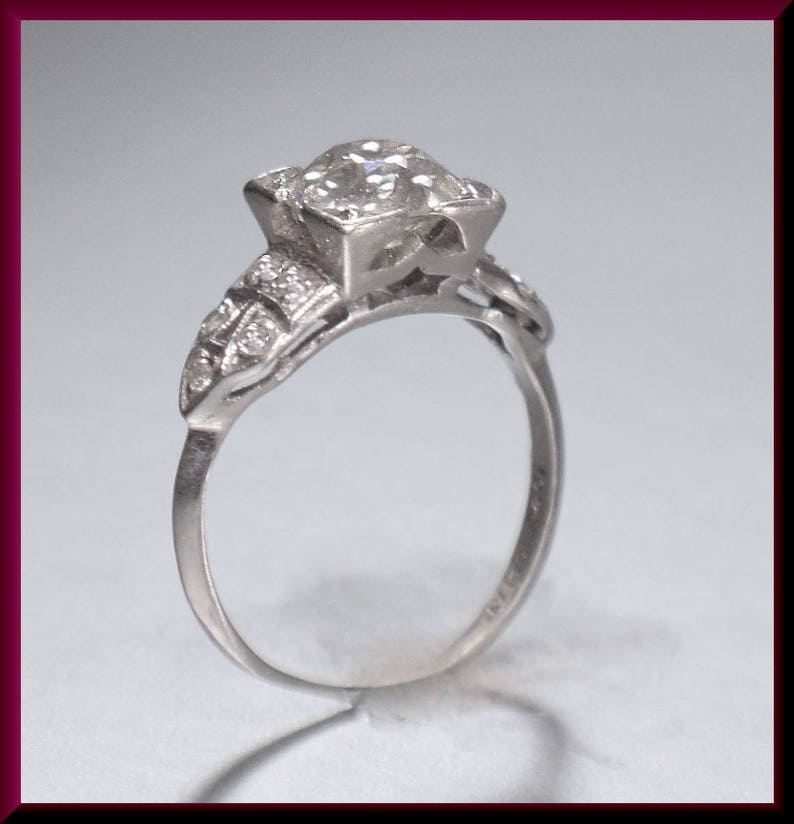 May include: A silver engagement ring with a large, round, clear diamond set in a prong setting. The band is decorated with smaller diamonds.