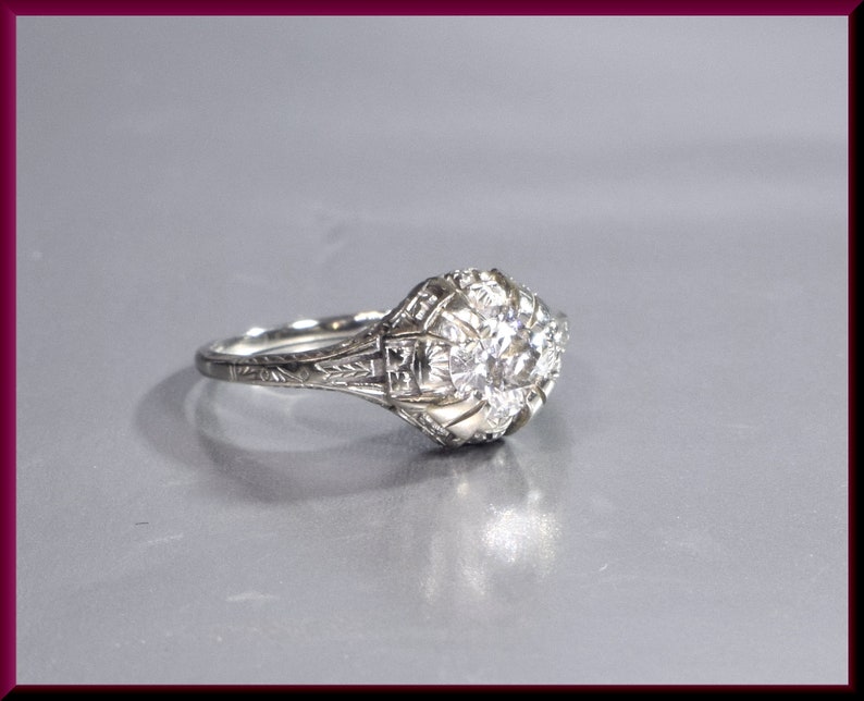 May include: A silver ring with a large, round, clear diamond set in a filigree design.