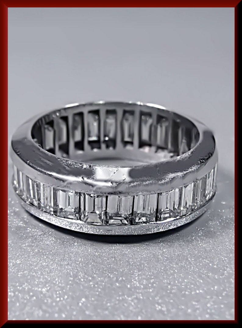 Pu&ograve; includere: Un anello a fascia d'argento con una fila di diamanti a baguette incastonati a canale.