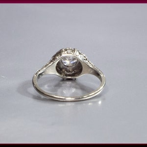 May include: A silver ring with a round, clear stone set in a decorative, filigree design.