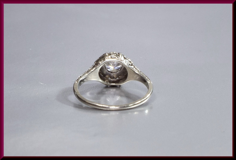 May include: A silver ring with a round, clear stone set in a decorative, filigree design.