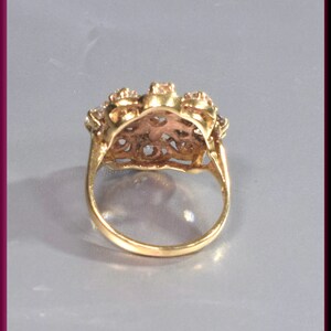 May include: A gold ring with a floral design and clear stones. The ring is set with a cluster of stones in the center and smaller stones around the band.