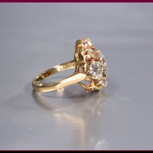 May include: A gold ring with a cluster of round, clear gemstones set in a floral design.