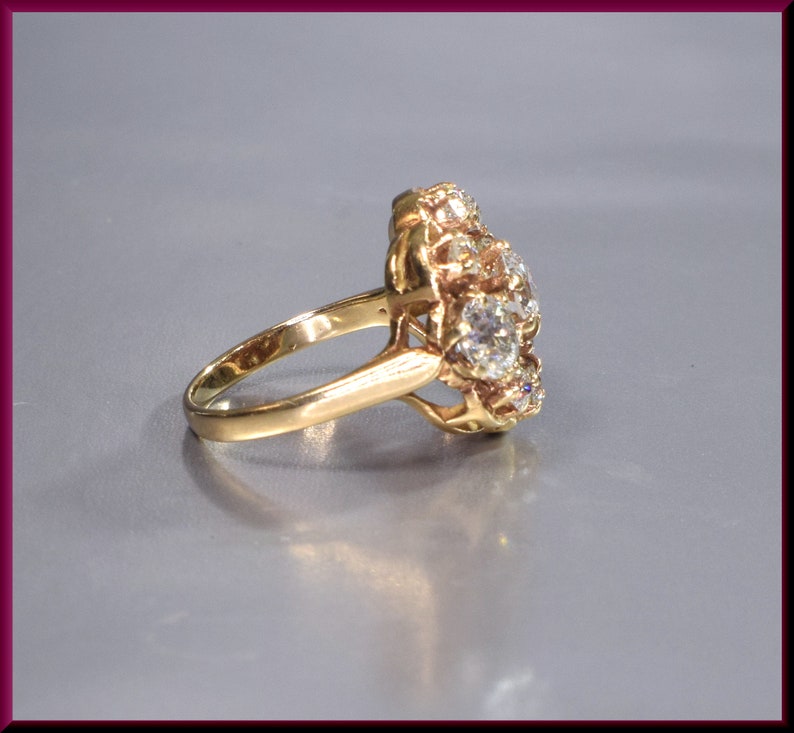 May include: A gold ring with a cluster of round, clear gemstones set in a floral design.