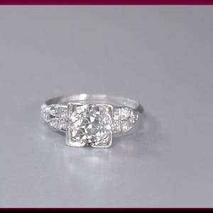 May include: A silver engagement ring with a round, clear diamond center stone and smaller diamonds set in the band.