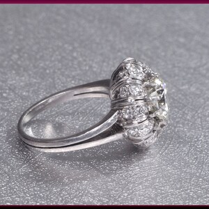 May include: A silver ring with a large, round, clear gemstone surrounded by smaller, clear gemstones.