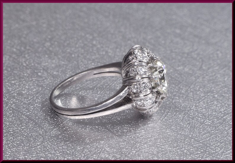May include: A silver ring with a large, round, clear gemstone surrounded by smaller, clear gemstones.