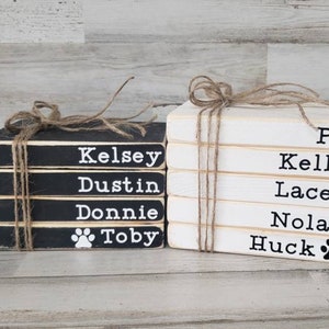May include: Two stacks of wooden blocks with names written on them. The top block of the stack on the left has a paw print. The top block of the stack on the right has a paw print and the name PJ. The names on the left stack are Kelsey, Dustin, Donnie, and Toby. The names on the right stack are PJ, Kelly, Lacey, Nolan, and Huck.