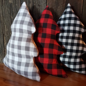 K&ouml;nnte beinhalten: Drei Weihnachtsbaum-f&ouml;rmige Kissen. Eines ist in grau-wei&szlig;em Gingham, eines in rot-schwarzem Buffalo-Karomuster und eines in schwarz-wei&szlig;em Gingham.