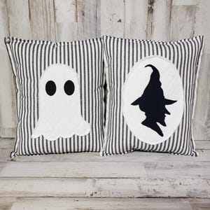 May include: Two black and white striped pillow covers with Halloween themed appliques. One pillow features a ghost and the other features a witch.