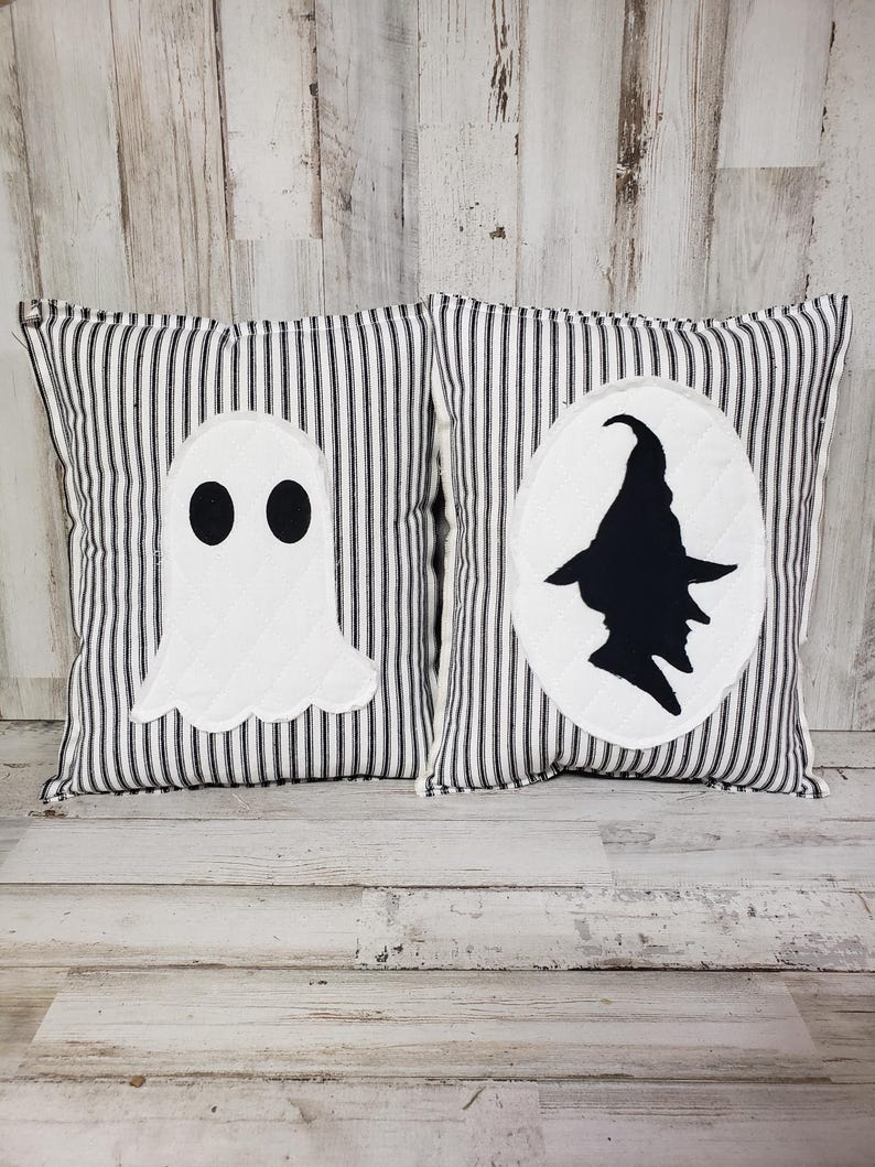 May include: Two black and white striped pillow covers with Halloween themed appliques. One pillow features a ghost and the other features a witch.