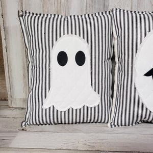May include: Two black and white striped pillow covers with white ghost appliques. The ghosts have black eyes.