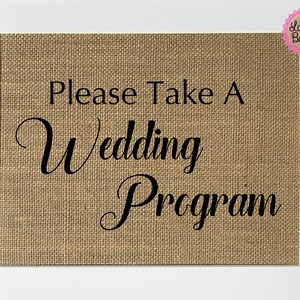 Puede incluir: Un letrero de arpillera con borde blanco y el texto "Please Take A Wedding Program" en letra cursiva negra.