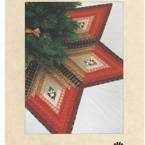 Può includere: Una trapunta a patchwork rosso, verde e marrone a forma di stella. La trapunta è decorata con piccole figure bianche ricamate. La trapunta è intitolata "Prairie Christmas" ed è realizzata da "Prairie Sky Creations".