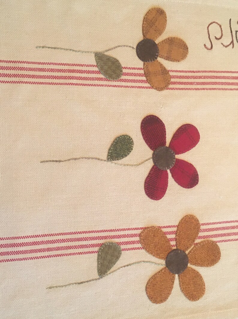May include: A white kitchen towel with red stripes features three embroidered flowers. The flowers are brown, red, and orange with green leaves. The word "Spring" is embroidered in the top right corner.