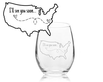 May include: A clear stemless wine glass with the etched outline of the United States and the phrase "I'll see you soon..." in a script font. A dotted line with hearts connects the states. The glass is on a white background.