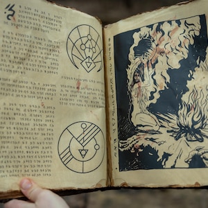 May include: Open book with aged, textured pages. The left page features handwritten text and geometric symbols. The right page displays a black and white illustration of a figure with flames and the words "IT CLAWS ON THE SKULL".
