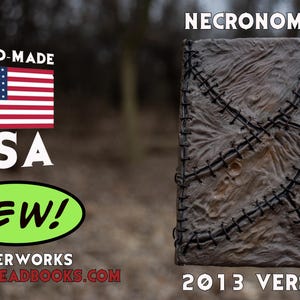 May include: A handmade, textured book cover with the title "Necronomicon" and "2013 Version" in white text. The cover is a mottled brown with black stitching. The American flag and the word "USA" are also visible.