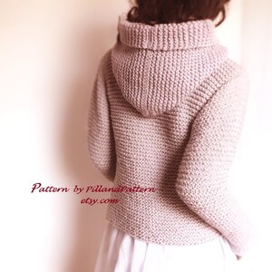 May include: A light pink knitted hooded sweater with a ribbed texture. The sweater is shown from the back and has a loose fit. The text "Pattern by PillandPattern etsy.com" is visible at the bottom of the image.