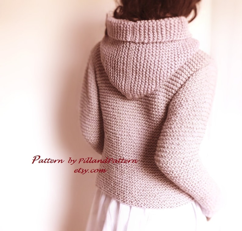 May include: A light pink knitted hooded sweater with a ribbed texture. The sweater is shown from the back and has a loose fit. The text "Pattern by PillandPattern etsy.com" is visible at the bottom of the image.