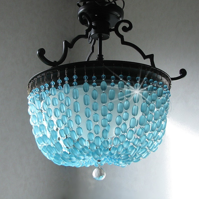 May include: A blue glass bead chandelier with a black metal frame. The chandelier has a crystal drop in the centre.