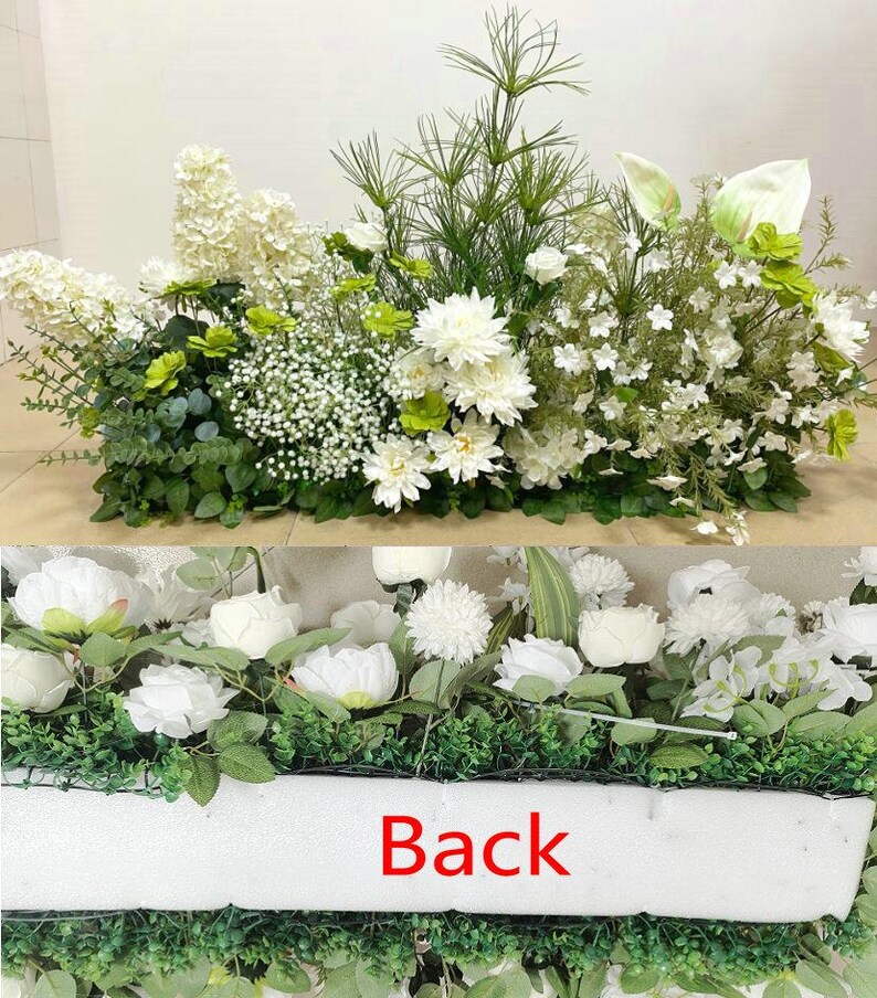 May include: A white artificial flower arrangement with a variety of flowers and greenery. The arrangement is in a white rectangular container with the word "Back" printed on the front.