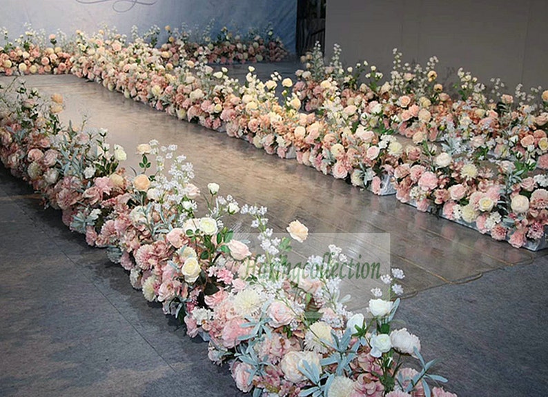 May include: A wedding aisle decorated with pink and white flowers. The flowers are arranged in rows along the aisle, creating a beautiful and romantic atmosphere.
