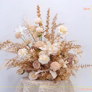 May include: A large, cream-colored floral arrangement with dried grasses and pampas grass. The arrangement is 50 cm tall and 52 cm wide.